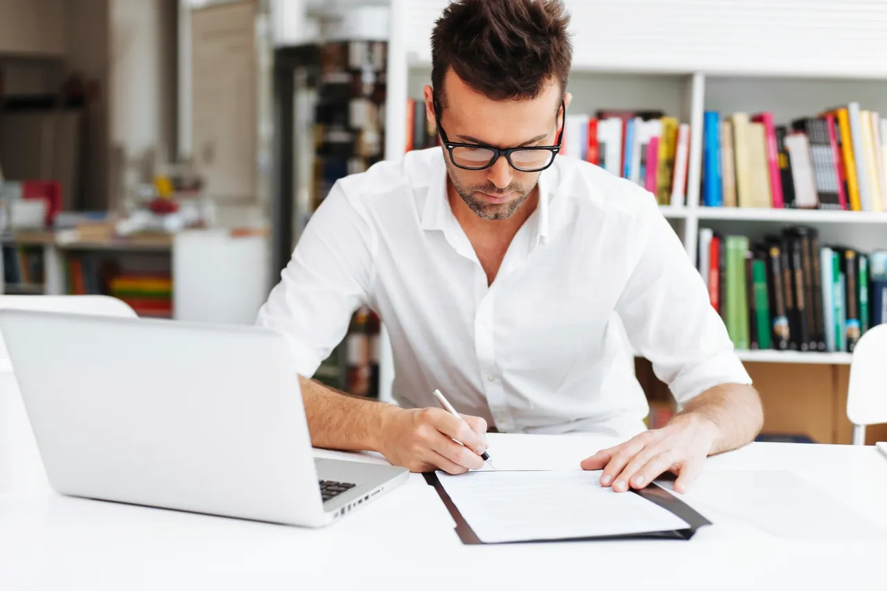 A man is holding a pencil and writing some notes