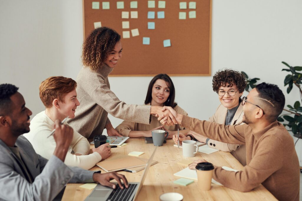 Group of diverse colleagues in a meeting, shaking hands and smiling