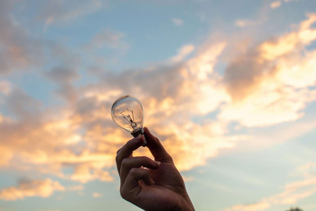 A Boy Holding A Light Bulb Up Towards The Sky